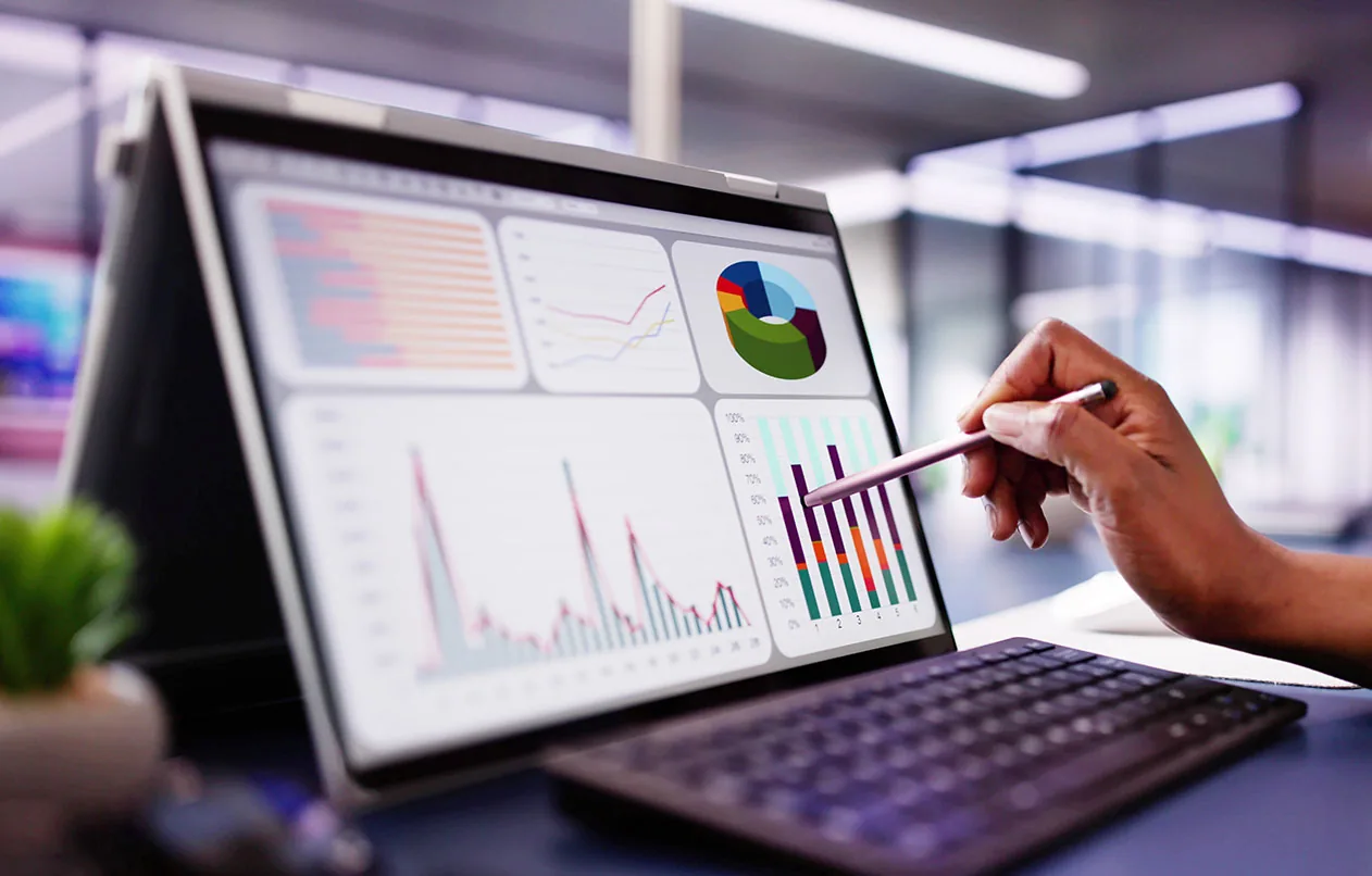 Hand mit Stift zeigt auf ein Dashboard mit Diagrammen zu Einkaufskennzahlen